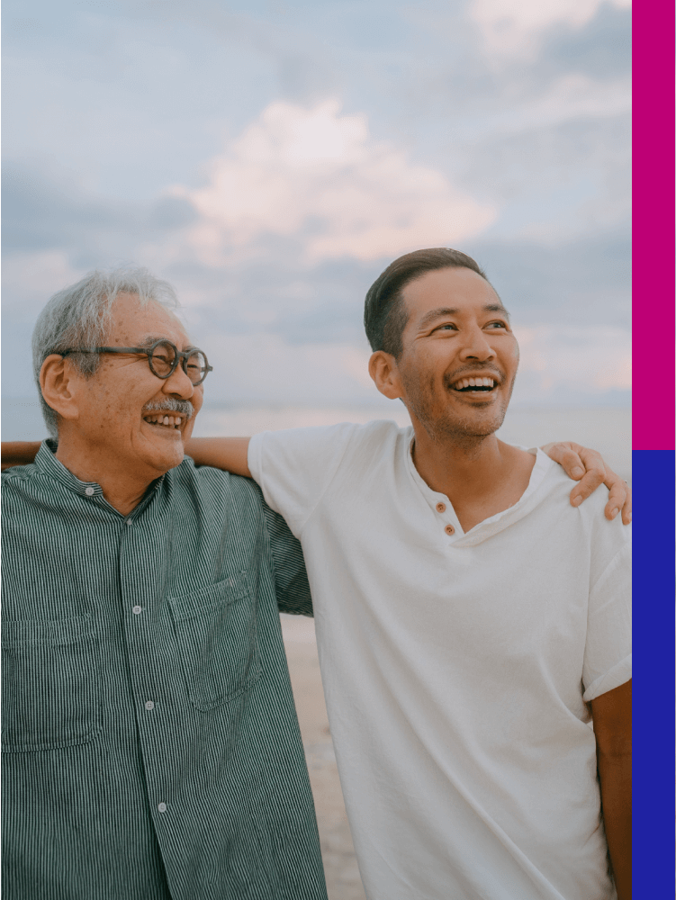 Photo of a younger man hugging an older man near the ocean