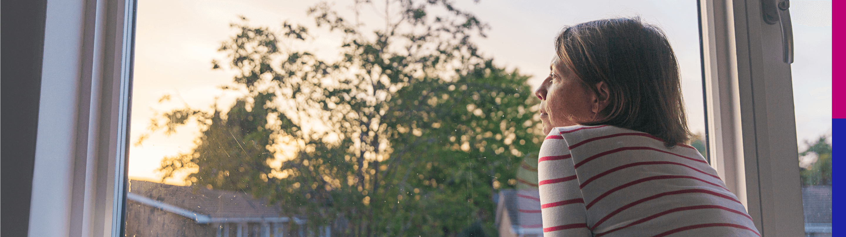 Photo of a woman looking through a window in early morning light