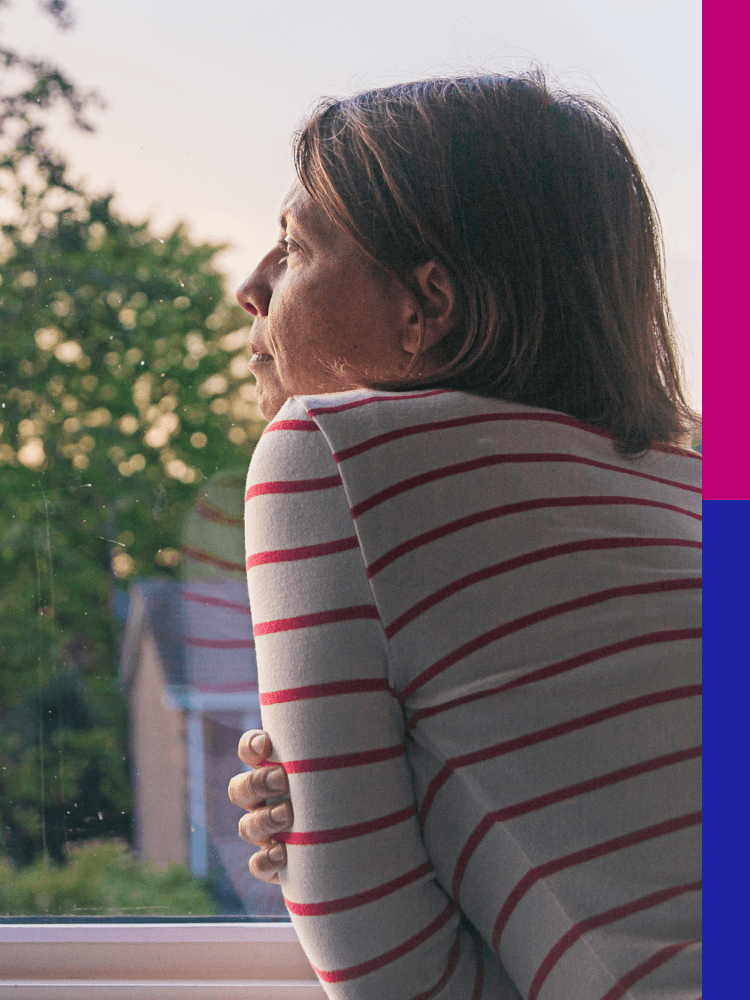 Photo of a woman looking through a window in early morning light