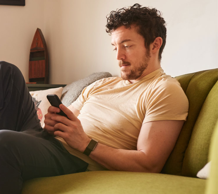 Photo of a man looking down at his phone sitting on a couch